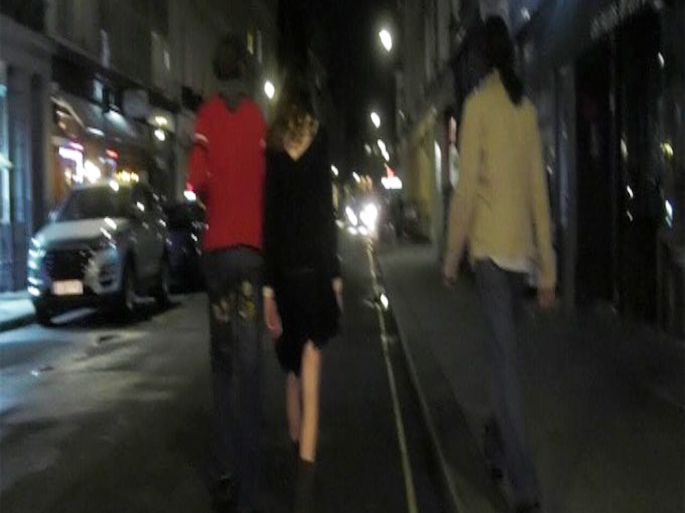 A blurry lofi image from behind of the band bar italia walking down a dark London street