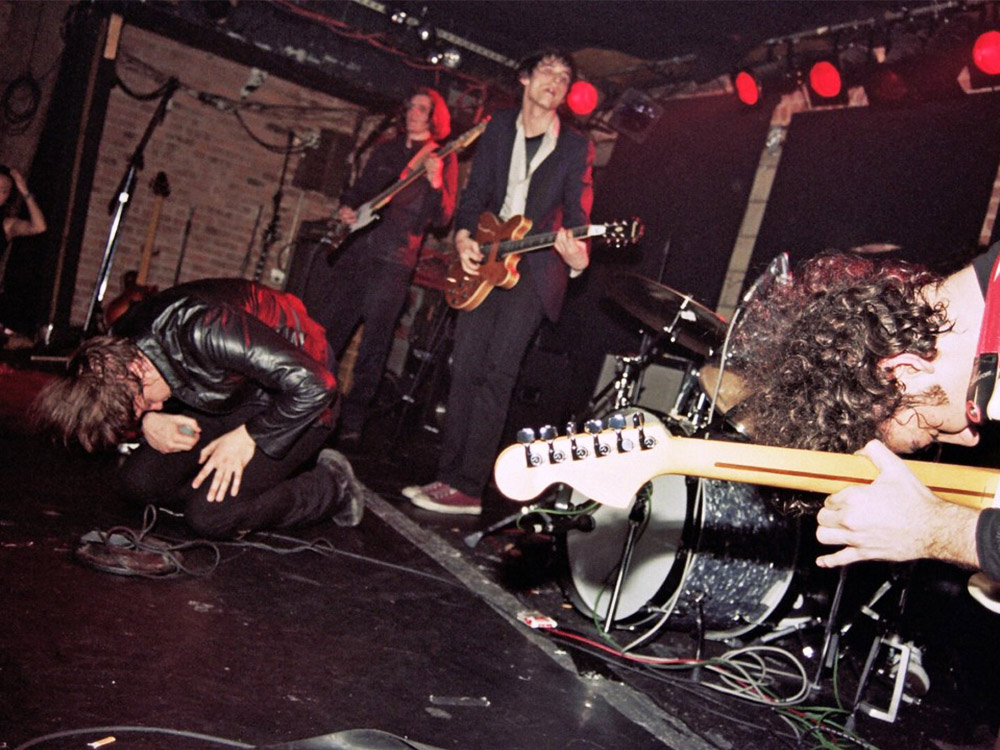 A rock band plays on stage, the photographer is taking this short right up against the stage