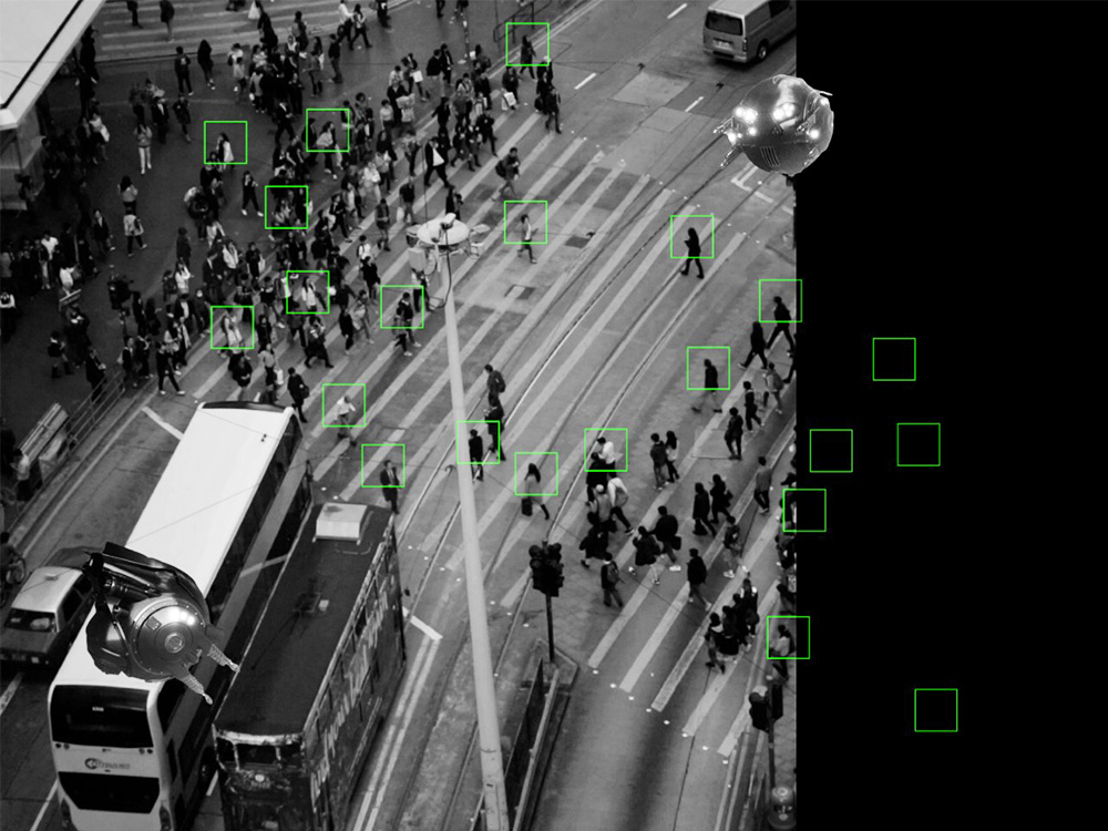 A birds' eye view through camera of a busy road crossing in Hong Kong. Small green squares target individuals across the image
