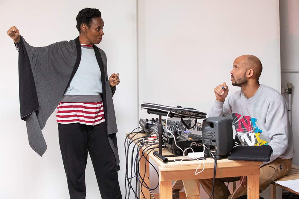 In rehearsals, the STARS director gestures and gives directions to DJ Michael Manners, who is in front of DJ decks and a mixer