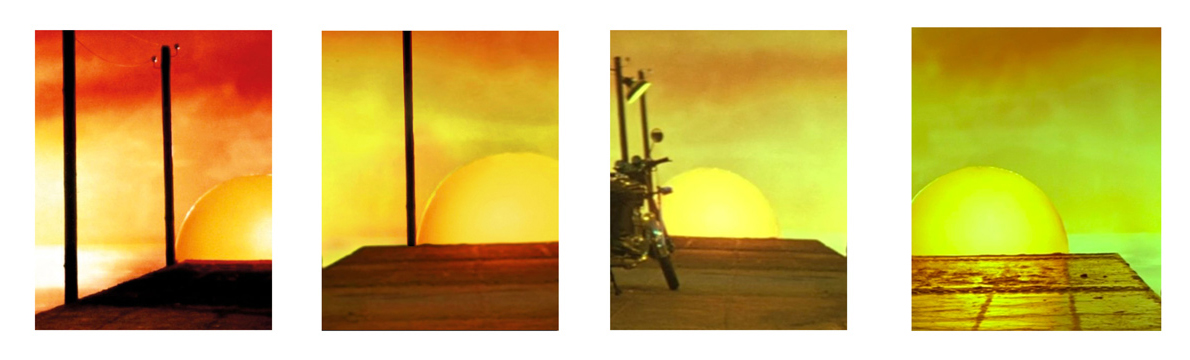 A series of four paintings depicting the sun fading behind a building in reds and yellows