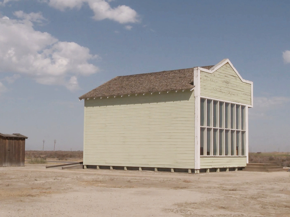 A beige building stands alone in a plain