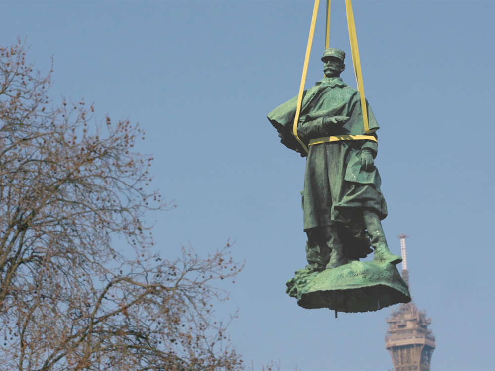 A statue of an old man being carried through the sky by yellow ropes