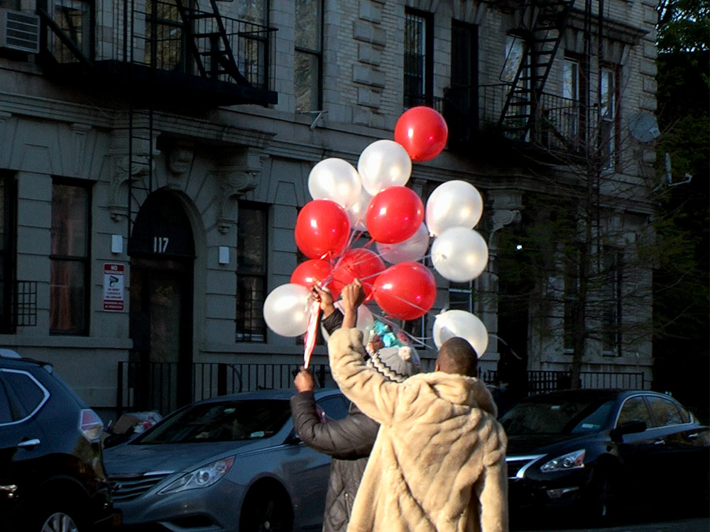 Two people standing on the street holding white and red balloons