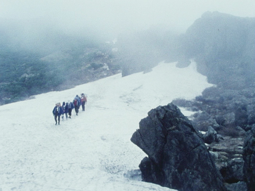 A group of hikers walk up a snowy mountain