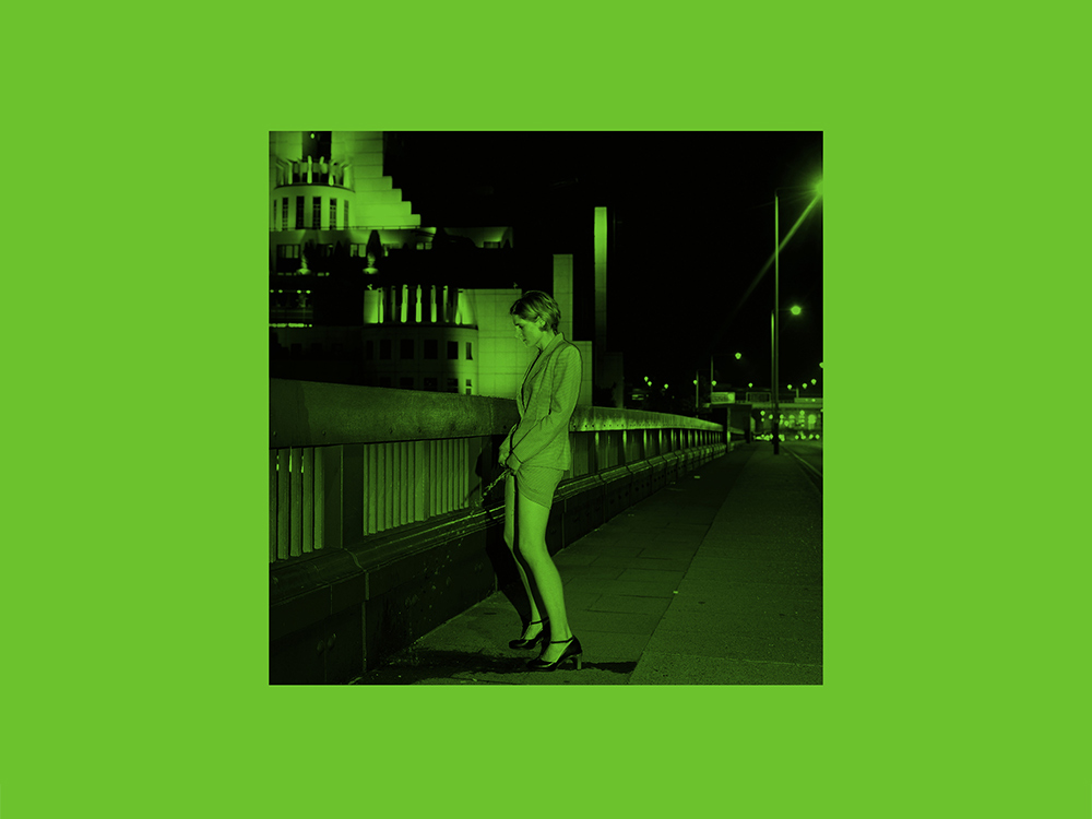 A woman in a suit and heels urinates on the side of a bridge. The picture is green-tinted and laid on a green background, like the book's cover