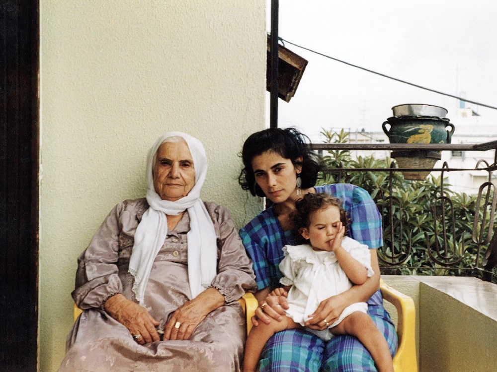 A Palestinian woman, her mother and daughter, sit on a balcony staring into the camera