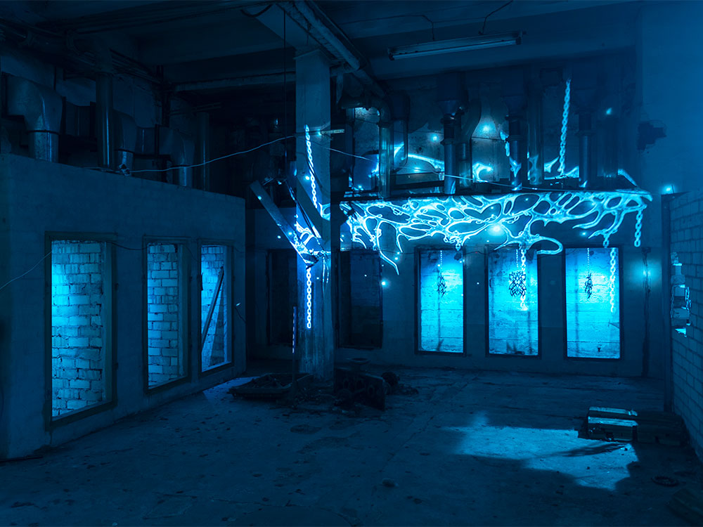 An art installation of light blue liquid-like lights in a factory space