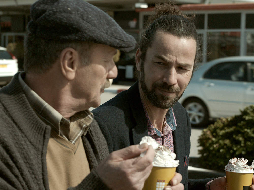 A father and son eat ice cream by the side of the road